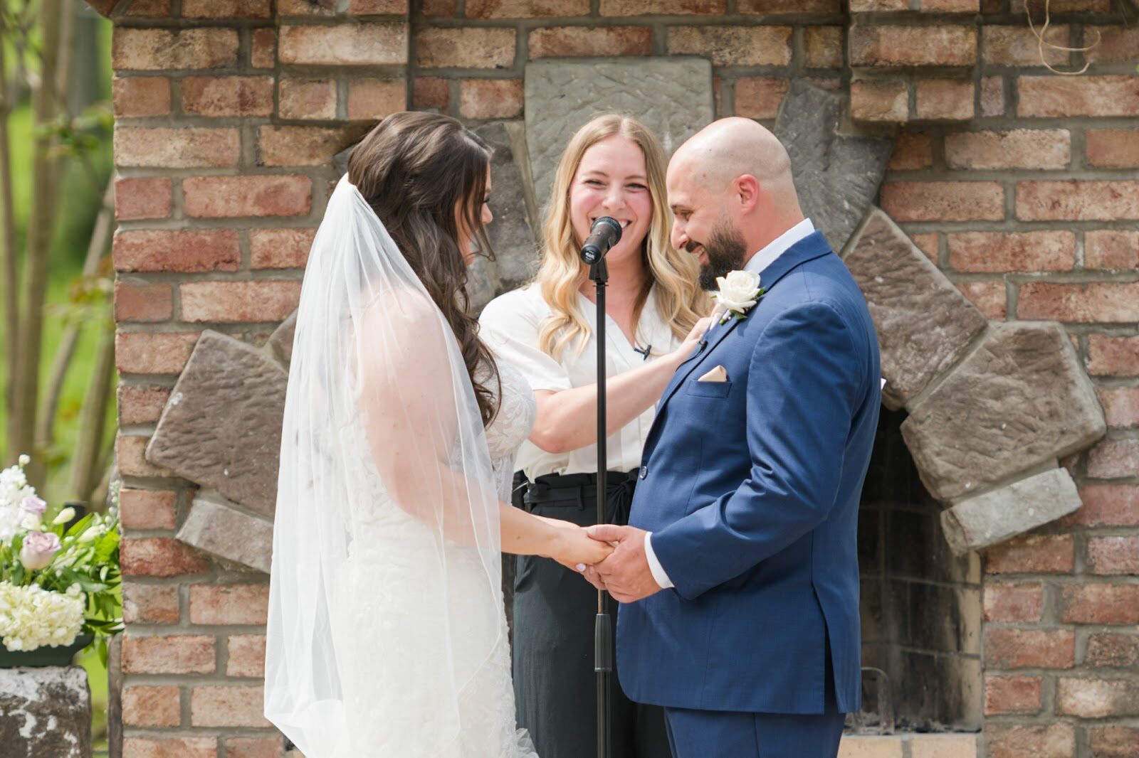 A couple exchanging vows by a brick fireplace