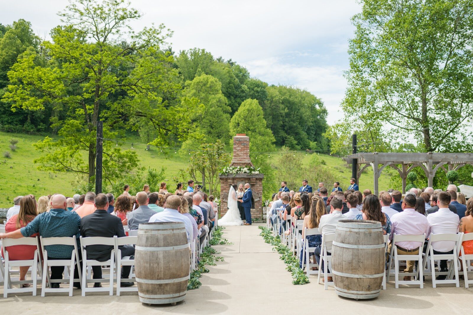 A rustic outdoor aisle lined with wine barrels